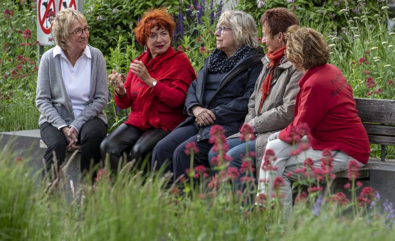 Damen sitzen zusammen auf einer Bank und unterhalten sich