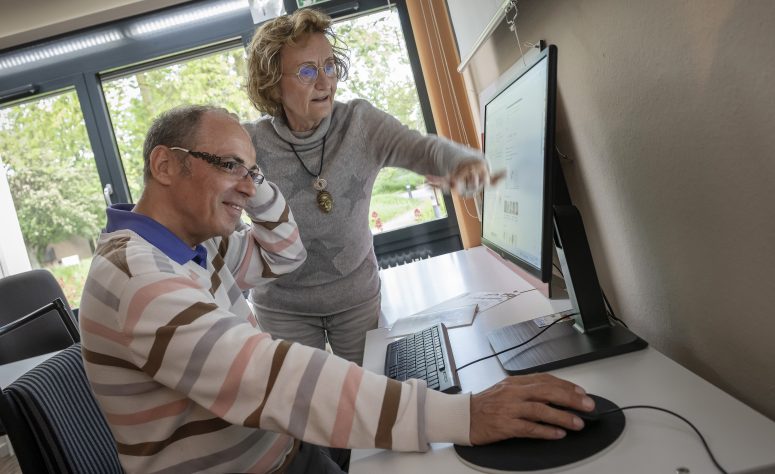 Herr zeigt Dame wie man mit einem Computer umgeht