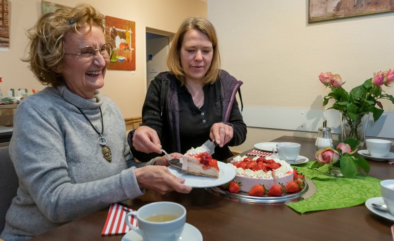 Dame freut sich über ein Stück Erdbeerkuchen