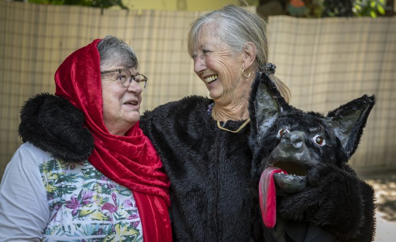 Zwei Damen lachen gemeinsam in Ihren Theaterkostümen von Rotkäppchen und der böse Wolf